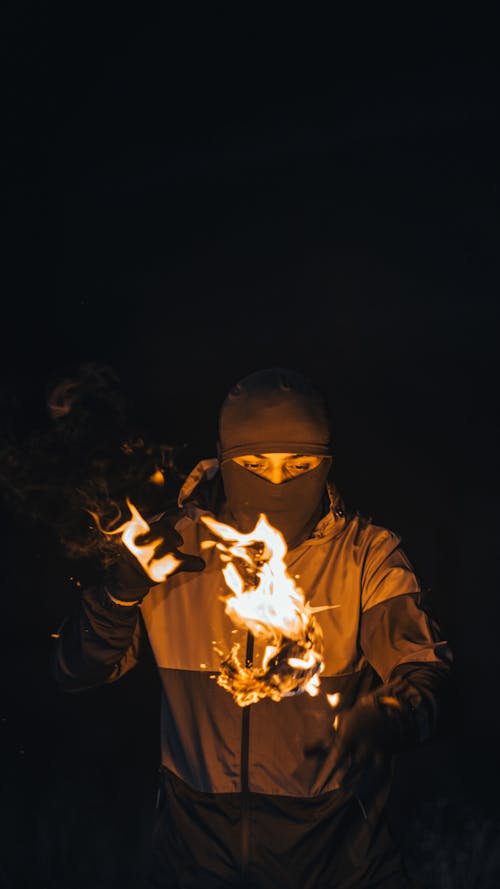 Fire over Man in Balaclava at Night