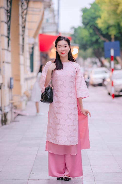 Model in Traditional Pink Dress and Silk Pants on the Sidewalk