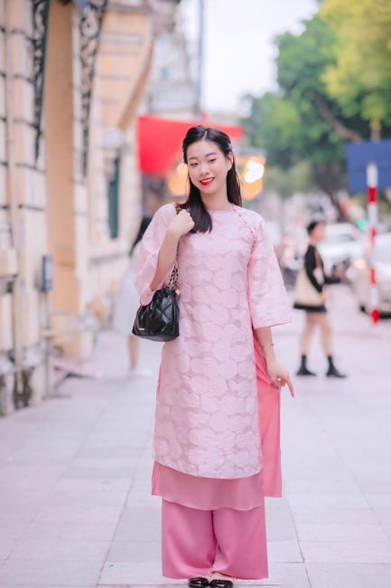 Elegant woman in a traditional pink dress on an urban street, showcasing cultural fashion.