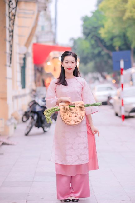 Woman in pink traditional dress standing on a bustling city street, capturing cultural charm.