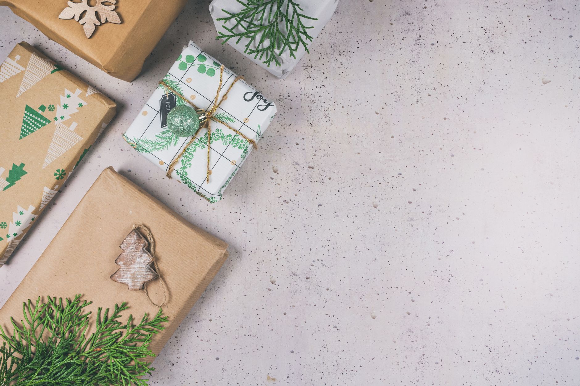 Top view of Christmas gifts wrapped in eco-friendly paper with natural decorations on a rustic background.