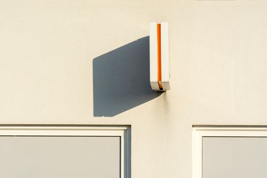 Close-up of a minimalist wall light creating a shadow against a white urban wall.