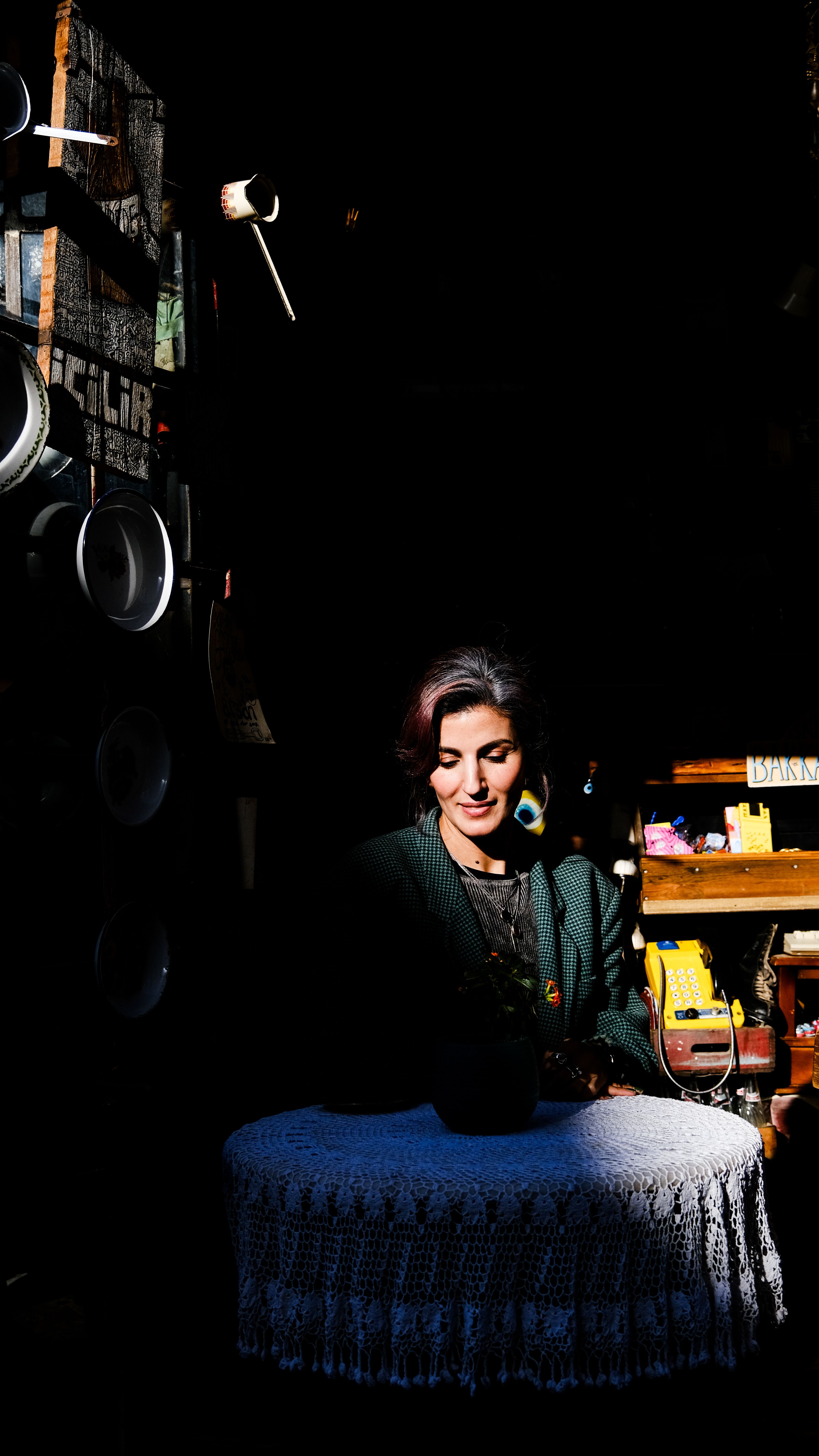 A woman sits at a lace-covered table in a sunlit, cozy room.
