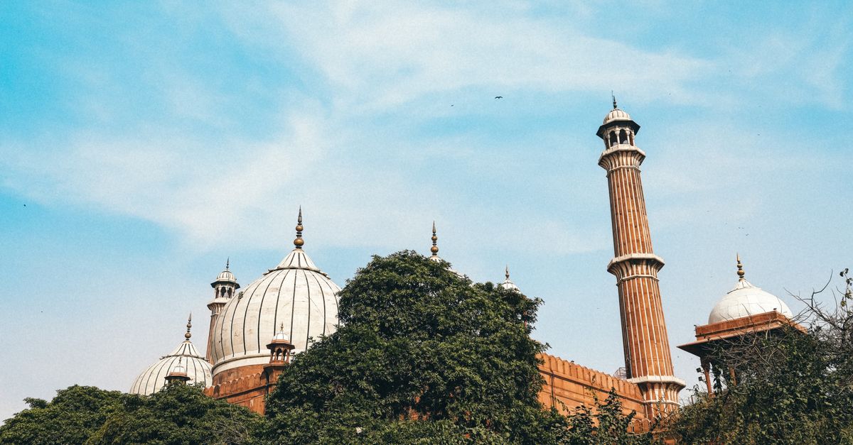 A vibrant view of a bustling street near a historic mosque in Delhi, India.