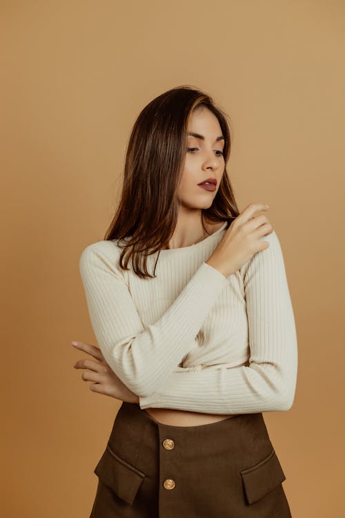A woman in a white sweater and brown skirt