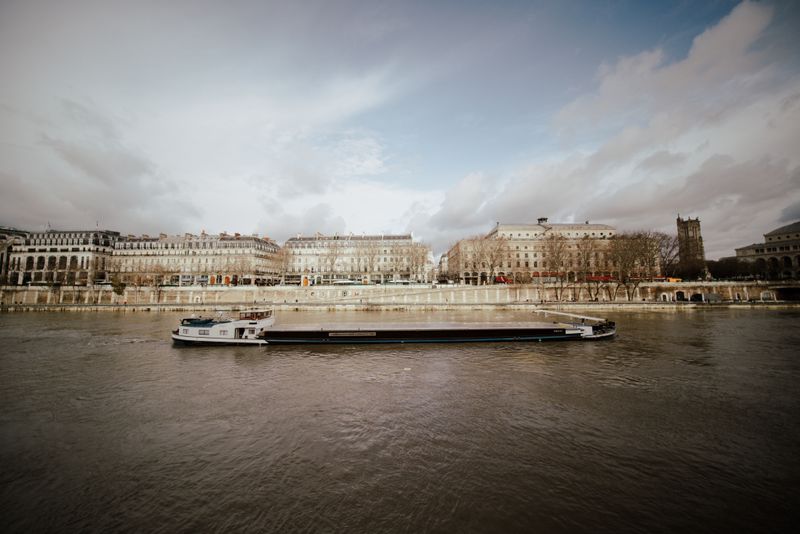 Elegant passenger boat cruising along a river with classic stone buildings on the near bank