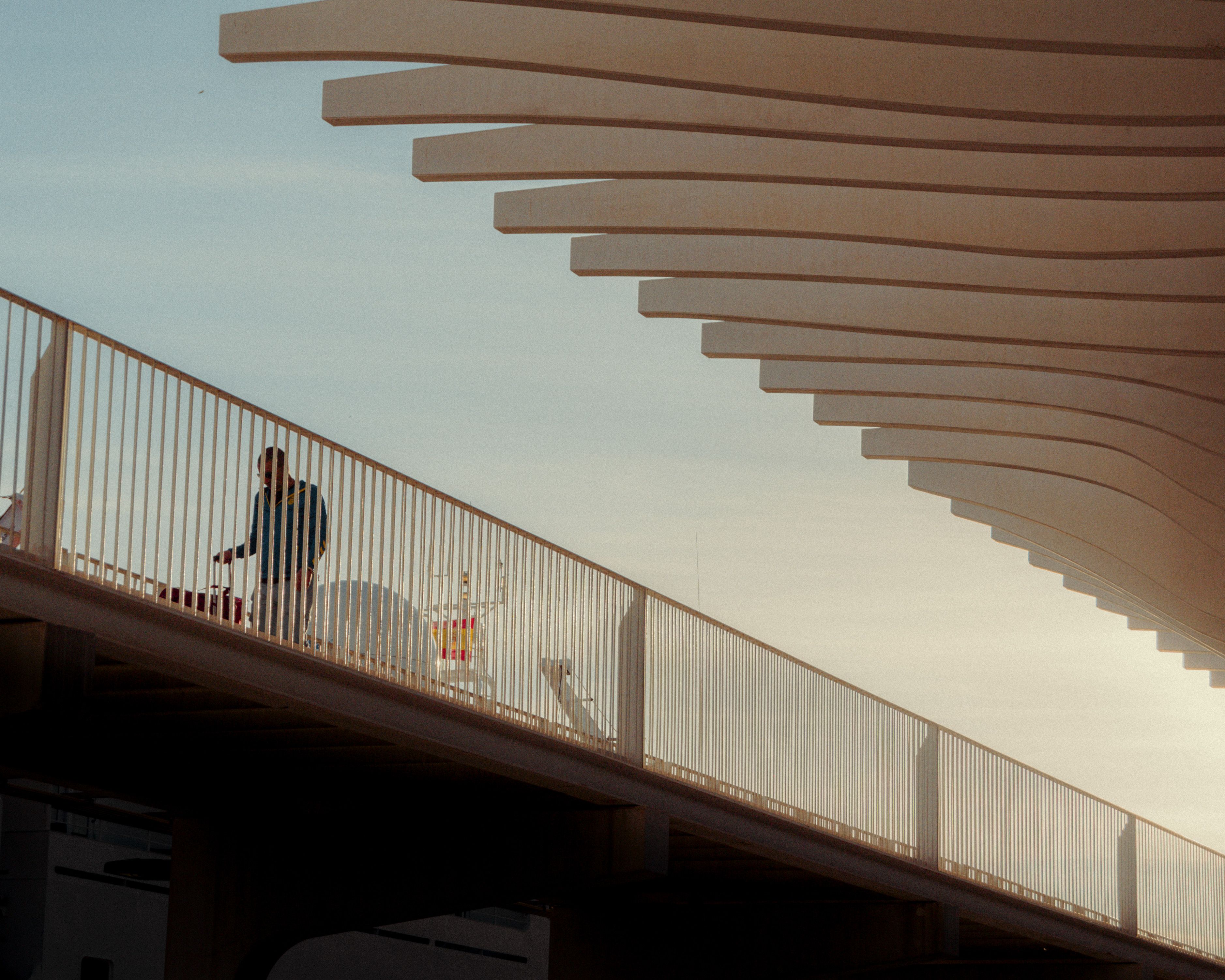 Man Walking behind Bridge Railing · Free Stock Photo