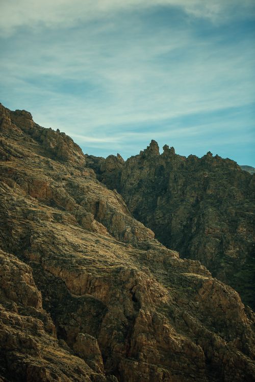 Free A dramatic view of rocky mountain terrain under a clear blue sky, showcasing nature's raw beauty. Stock Photo