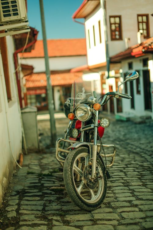 Free Vintage motorcycle parked in a charming cobblestone alley of a historic urban area. Stock Photo