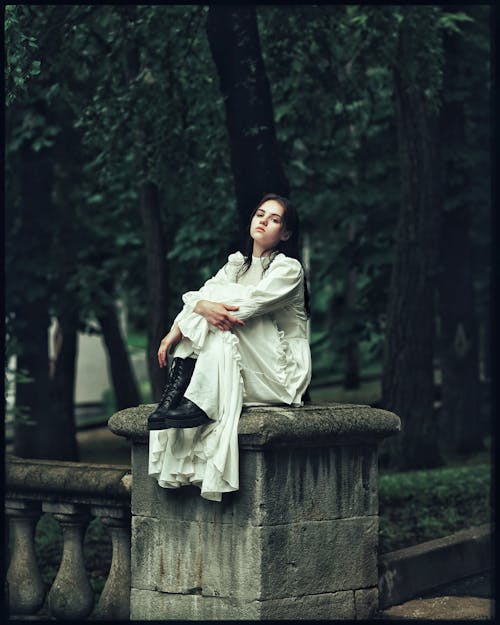 Woman in White Dress Sitting on Wall in Park