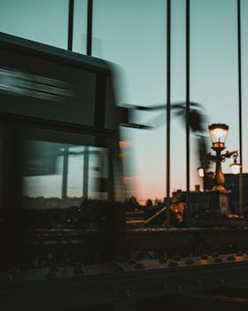 Blurred train crossing a bridge in Budapest at sunset, capturing urban motion.
