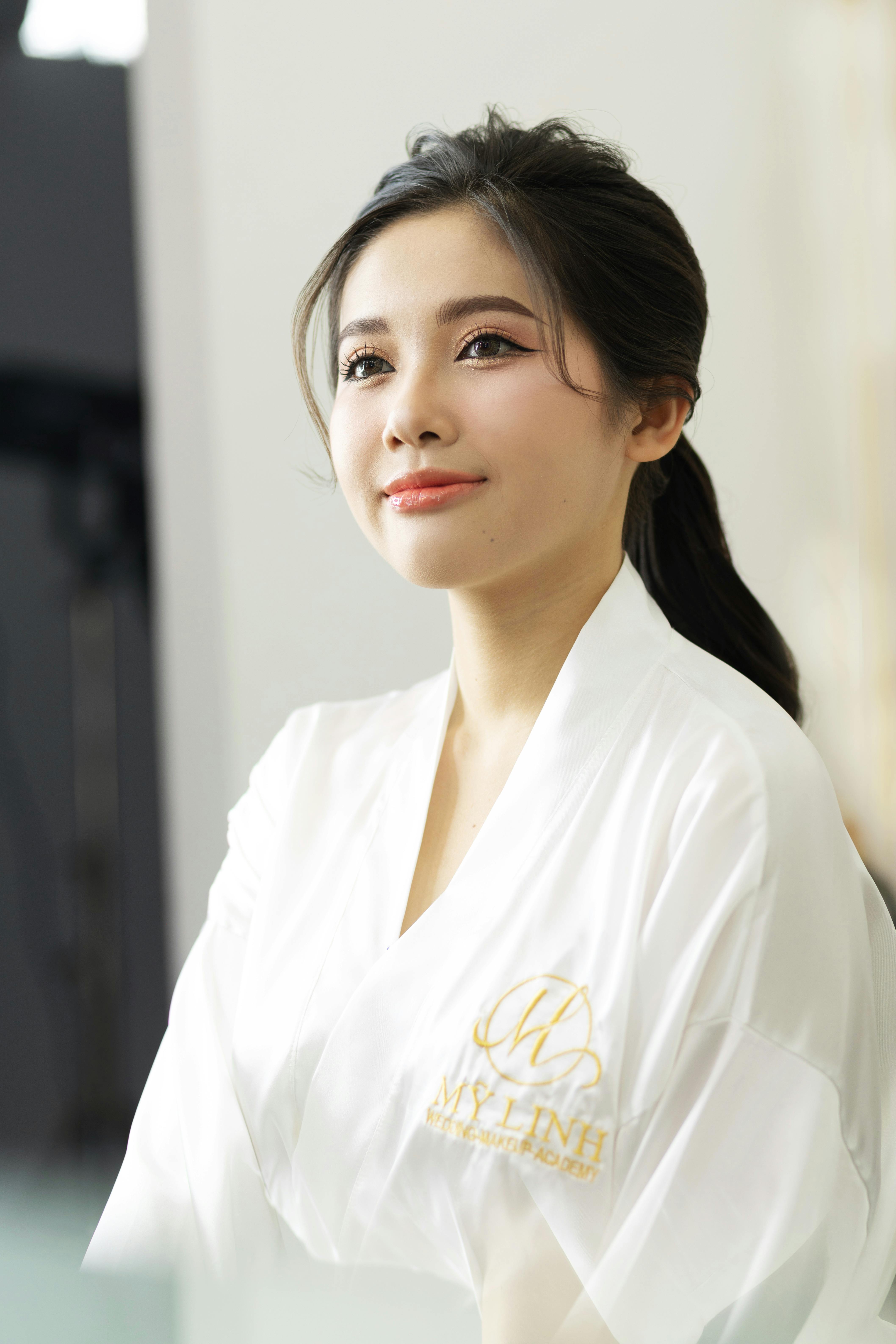 Portrait of a young woman in a white bathrobe with a serene expression indoors.