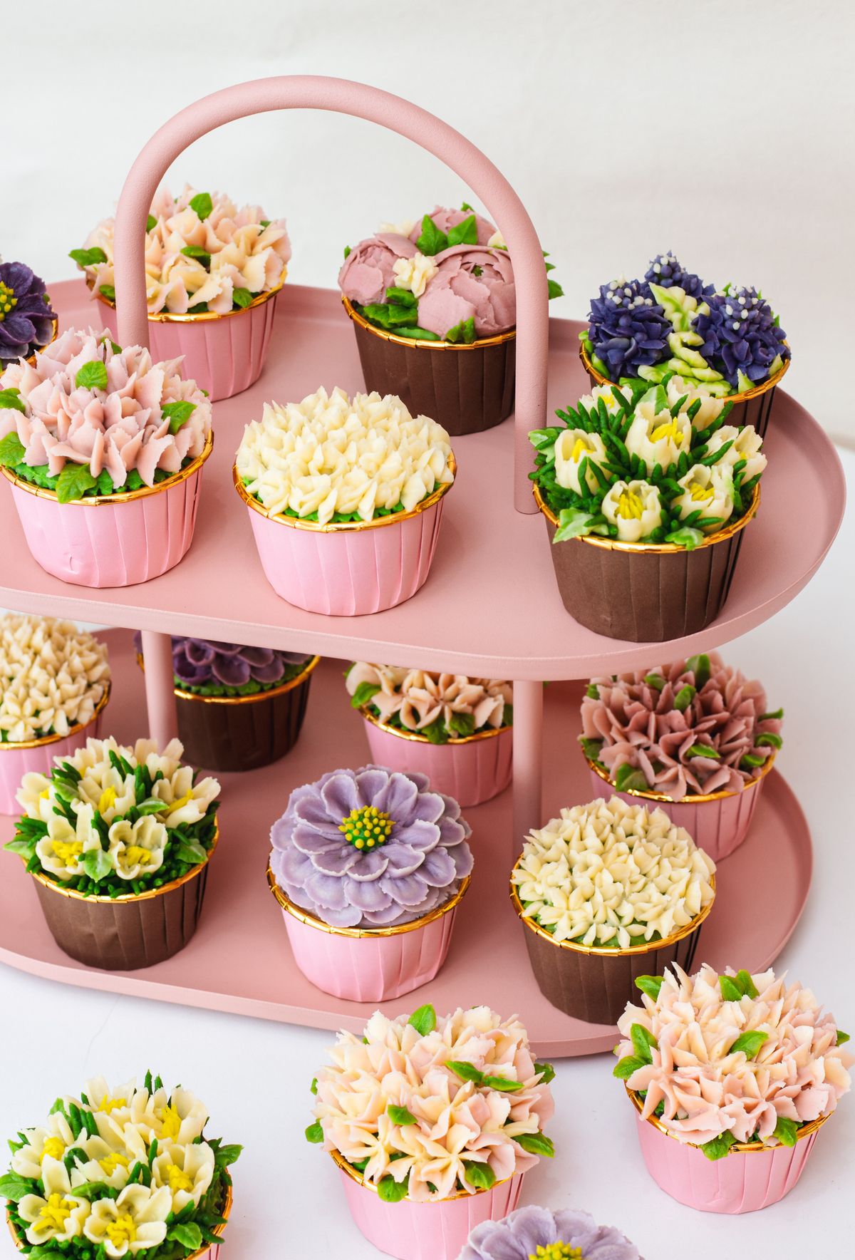 Cupcake tower on a tiered stand with flower-decorated cupcakes