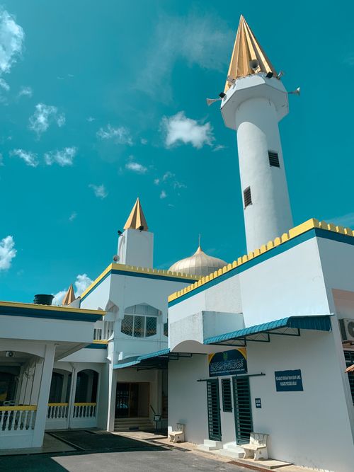 Free Low-angle view of the Perlis State Mosque with golden domes and minarets against a bright blue sky in Malaysia. Stock Photo