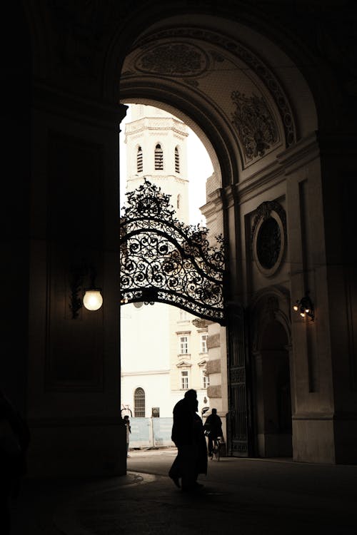 Silhouettes of Pedestrians Walking under an Arch at Hofburg, Vienna, Austria 