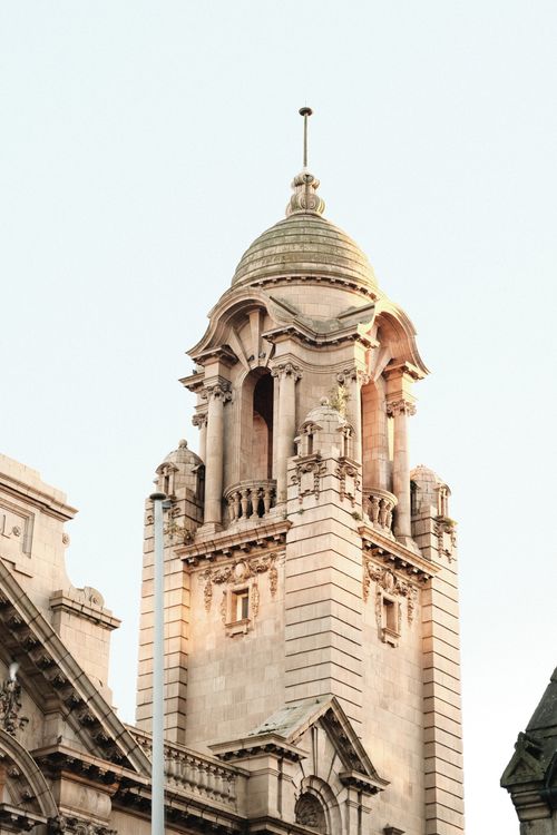 Free Close view of a historic stone tower bathed in warm sunlight, showcasing classic English architecture. Stock Photo