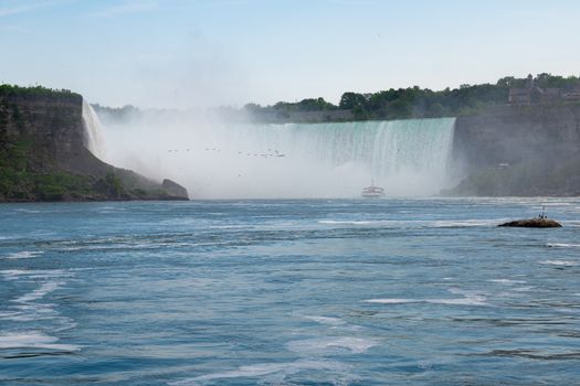 Capture the breathtaking view of Niagara Falls with mist and greenery in Ontario, Canada.