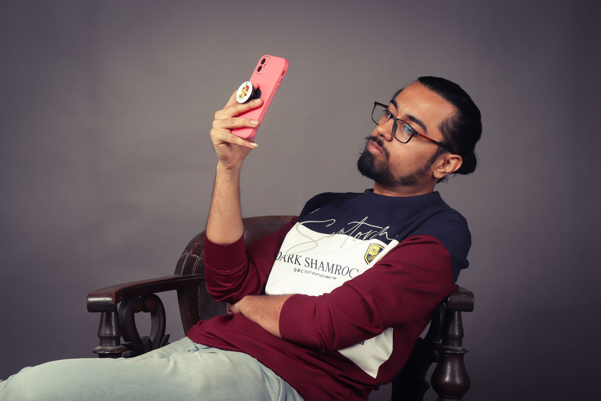 A Bearded Man Sitting on a Chair and Using His Phone