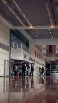 People walking through a modern airport terminal with luggage.
