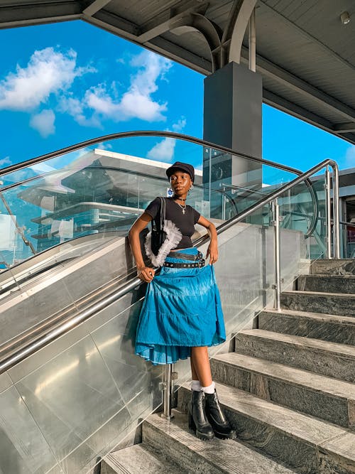 Model in a Blue Skirt and High-Heeled Boots Standing on the Stairs