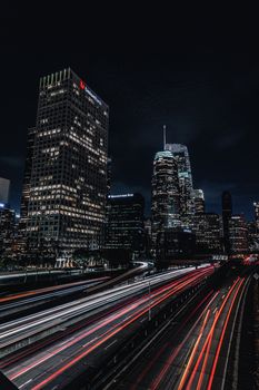Dynamic cityscape of Los Angeles featuring skyscrapers and vibrant traffic light trails at night.