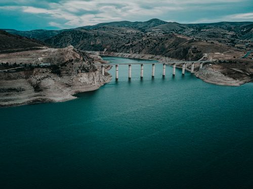 Free Scenic aerial view of a bridge crossing the turquoise waters in Felahiye, surrounded by rugged hills. Stock Photo