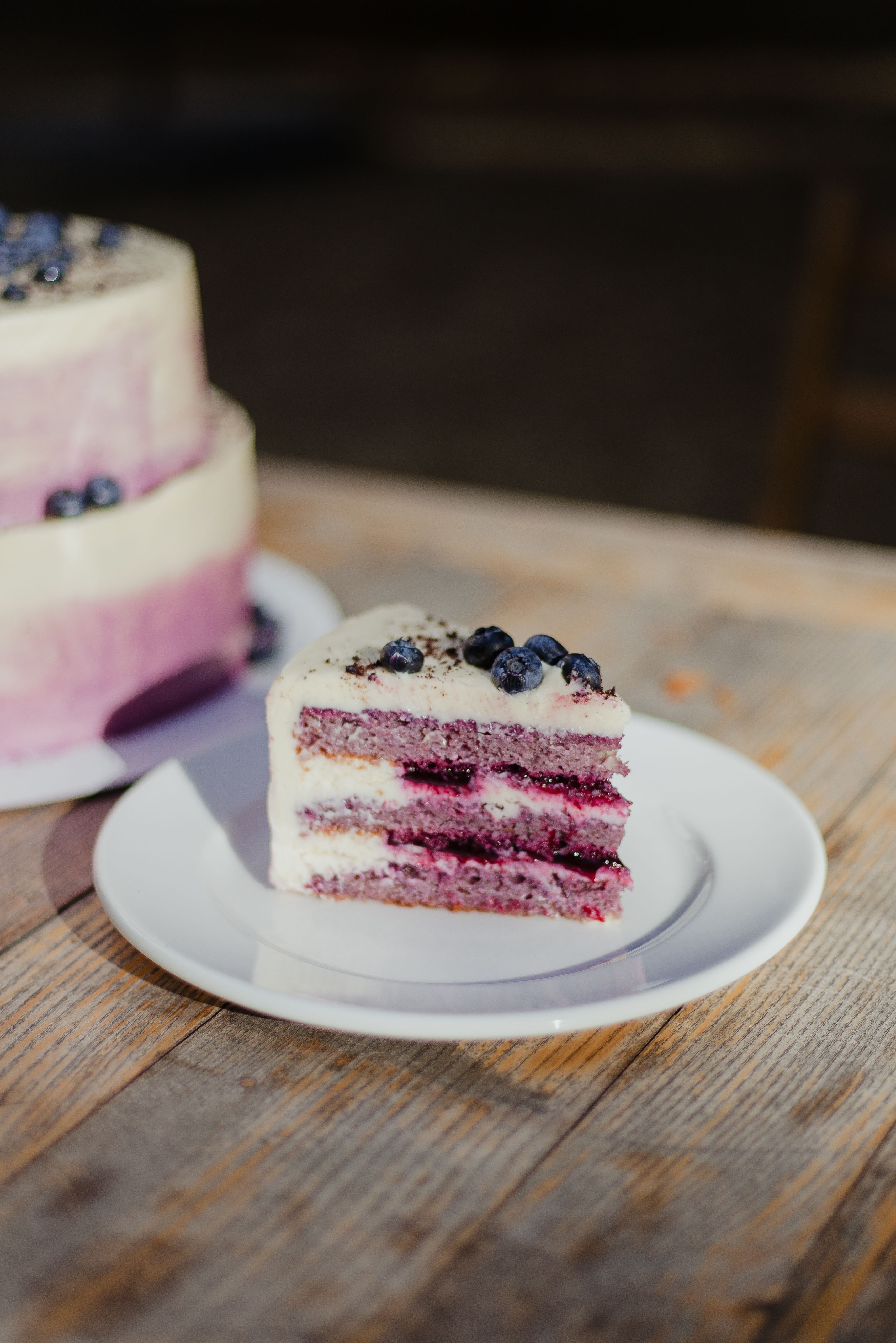A delicious slice of blueberry layer cake on a wooden table, perfect for dessert lovers.
