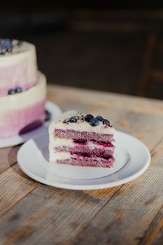 A delicious slice of blueberry layer cake on a wooden table, perfect for dessert lovers.