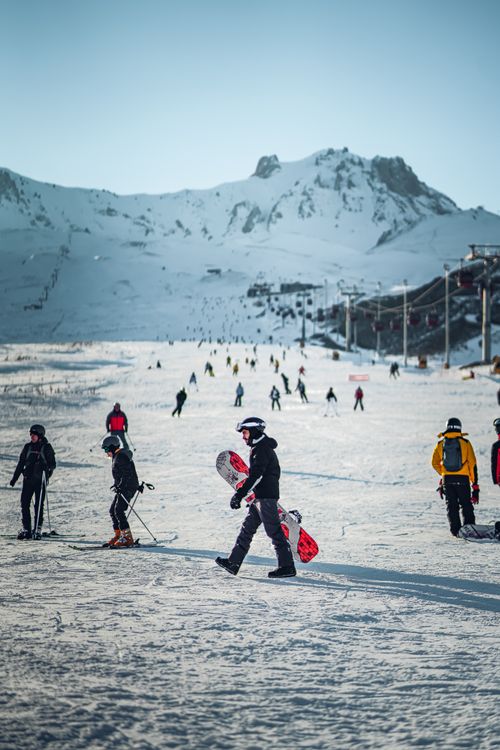 Free Skiers and snowboarders on a snowy mountain slope during winter, capturing a vibrant ski holiday scene. Stock Photo