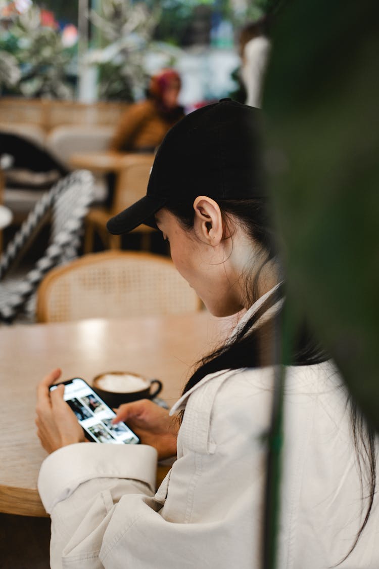 Woman Drinking Coffee And Checking Phone In A Restaurant 