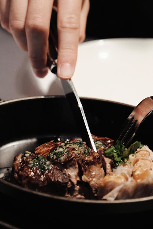 Close-up of a Person Cutting Meat on a Plate