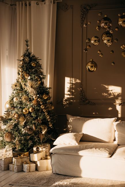 Cozy living room with decorated Christmas tree and gifts under warm sunlight.