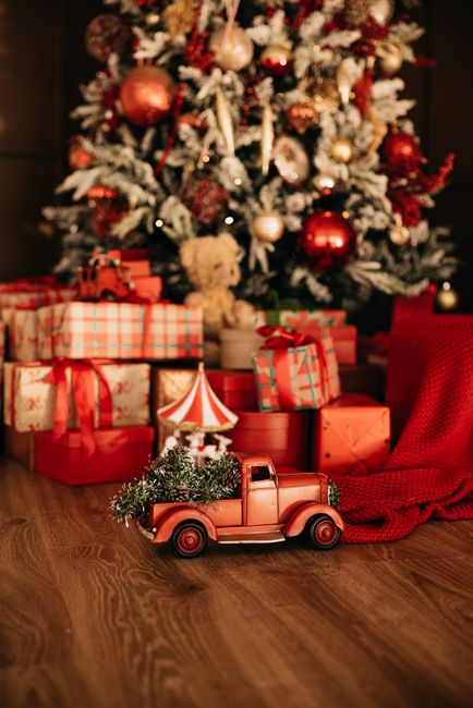 Decorated Christmas tree with wrapped gifts and a vintage toy truck in a cozy indoor setting.