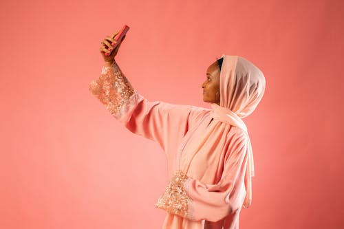 Woman in Pink Dress and Headscarf Taking Selfie
