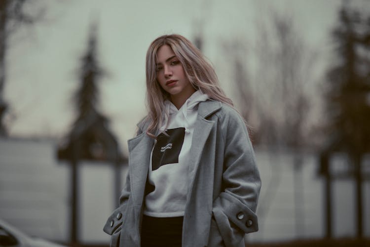 Young Fashionable Woman In A Hoodie And Coat Standing Outside 