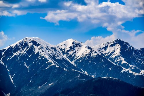 Free Breathtaking view of snow-capped mountains with vivid blue skies and scattered clouds. Stock Photo