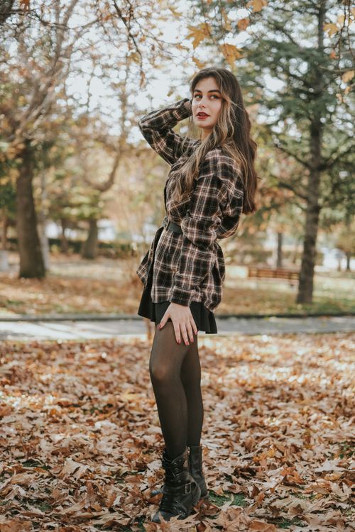 Free Elegant woman with long brown hair poses in autumn park, showcasing fashion style amidst fallen leaves. Stock Photo