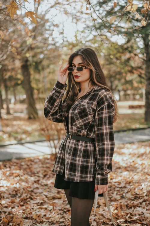 Free Stylish woman in autumn attire posing in a park surrounded by fall foliage. Stock Photo