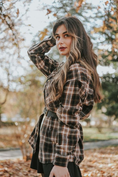 Free Young woman posing in a checkered outfit outdoors during fall season. Stock Photo