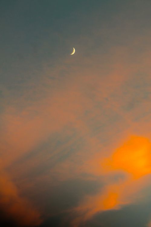 Free Aesthetic view of a crescent moon against a colorful sunset sky with orange and blue hues. Stock Photo