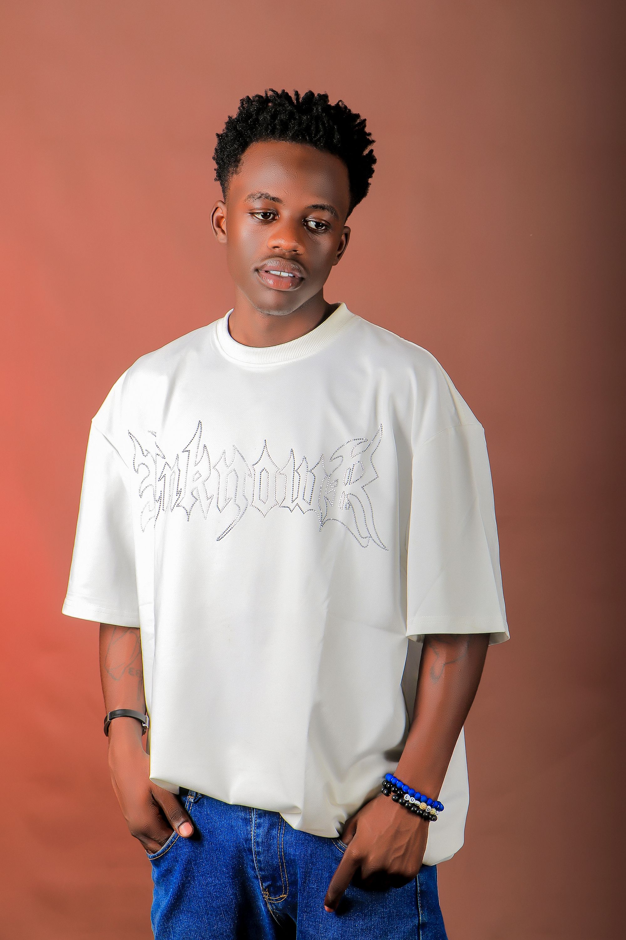 Young man in casual streetwear posing in a studio with a relaxed vibe.
