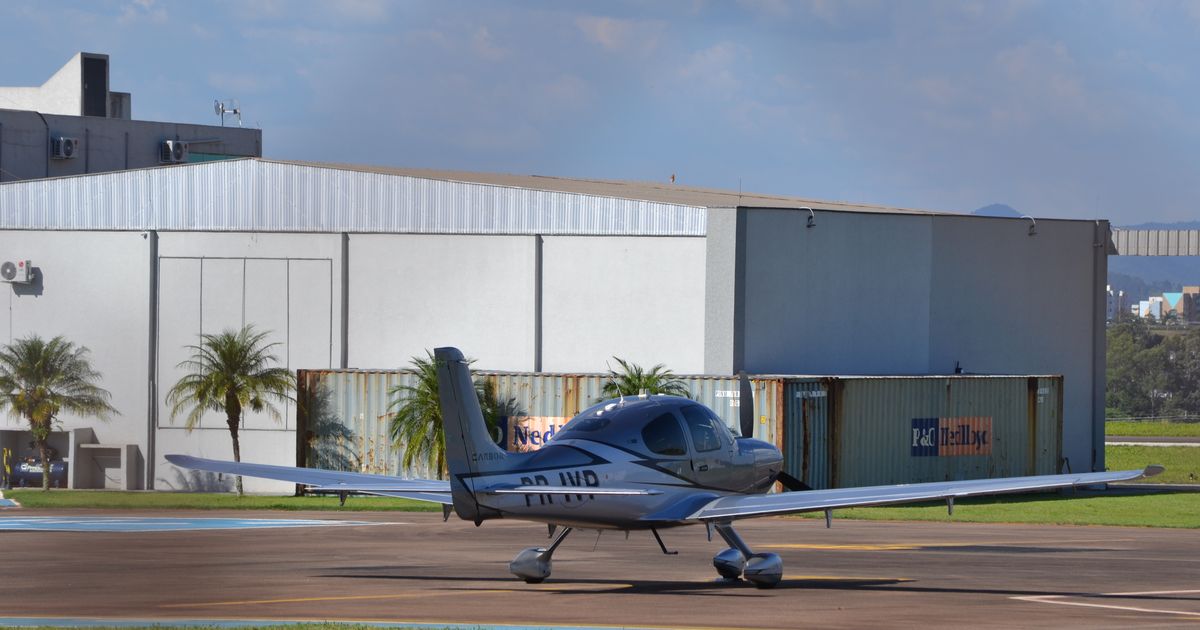A private airplane parked outside a hangar at a small airport.