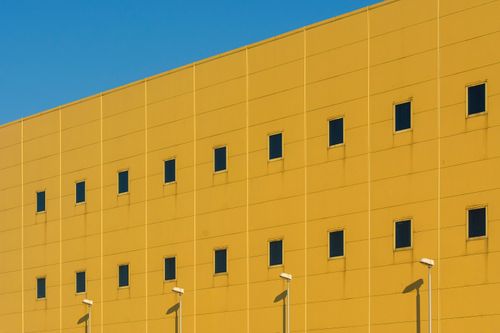 Free Modern urban architecture featuring a yellow building facade with uniform square windows. Stock Photo
