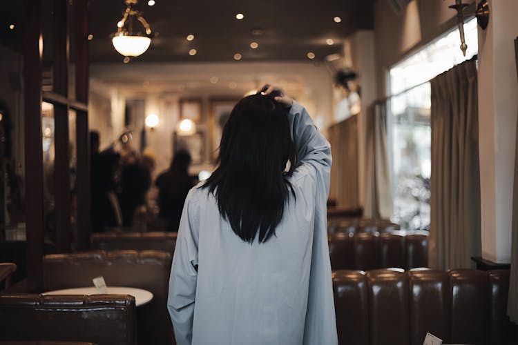 Back View Of A Woman Walking In A Restaurant And Fixing Her Hair