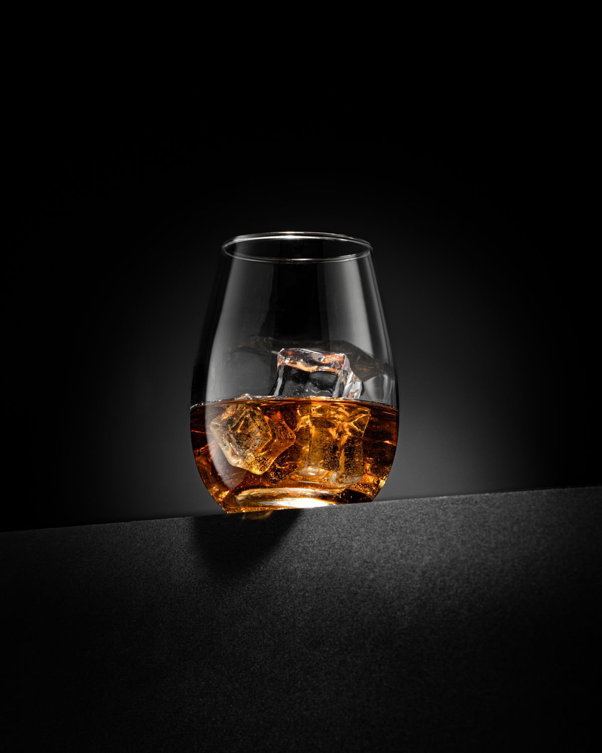 Whisky glass with ice on dark background