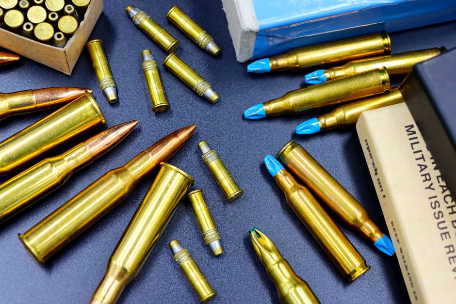 Photo by Marta Branco Top view of various rifle and handgun bullets on a dark surface, showcasing their golden casings.