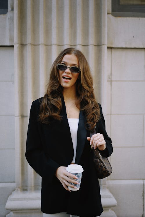 Woman with Long Brown Hair Holding a Disposable Cup of Coffee and a Bag