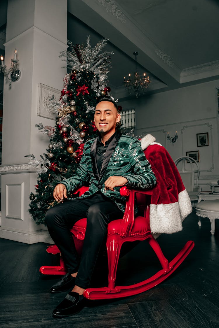 Smiling Man Sitting In A Rocking Chair By A Christmas Tree