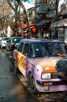 Colorful vintage car parked on a charming urban street, evoking nostalgia.