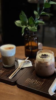 A cozy coffee setup showcasing iced beverages on a wooden table with plant decor.